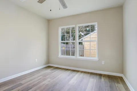 an empty room with wooden floor and windows
