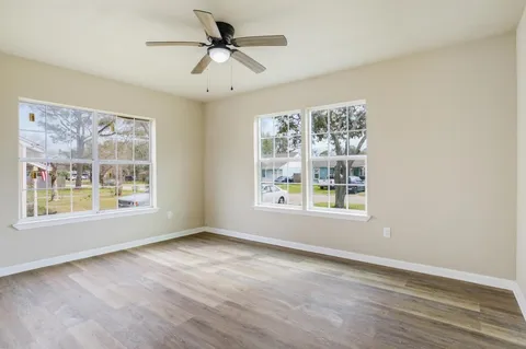 a view of an empty room with a window and wooden floor