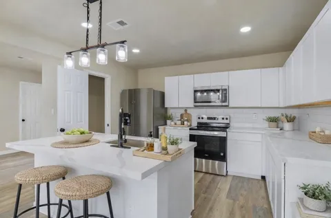 a kitchen with kitchen island a dining table chairs stainless steel appliances and cabinets