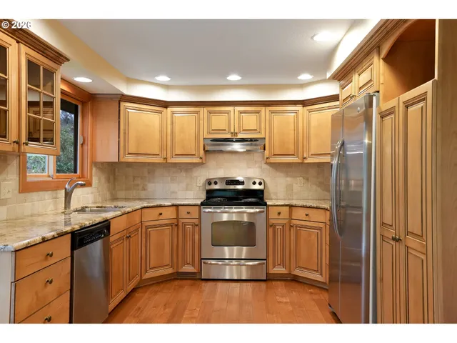 a kitchen with stainless steel appliances granite countertop a stove a sink and a refrigerator