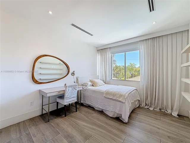 a bedroom with a bed a mirror and a window