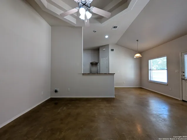 an empty room with a chandelier fan and windows