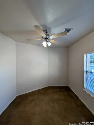 an empty room with a ceiling fan and window