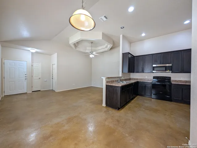 a large kitchen with stainless steel appliances kitchen island granite countertop a stove a sink dishwasher and a microwave with wooden cabinets