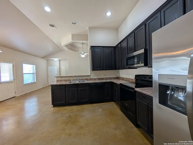a large kitchen with stainless steel appliances granite countertop a stove a sink dishwasher and a fireplace with wooden floor
