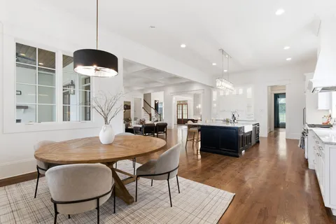 a dining room with wooden floor and chandelier