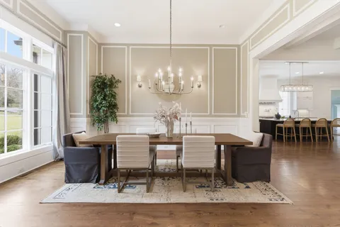 a living room with couches a table and chairs with wooden floor