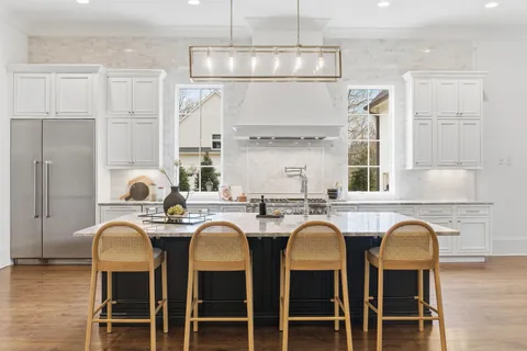 a kitchen with stainless steel appliances granite countertop a dining table chairs and white cabinets