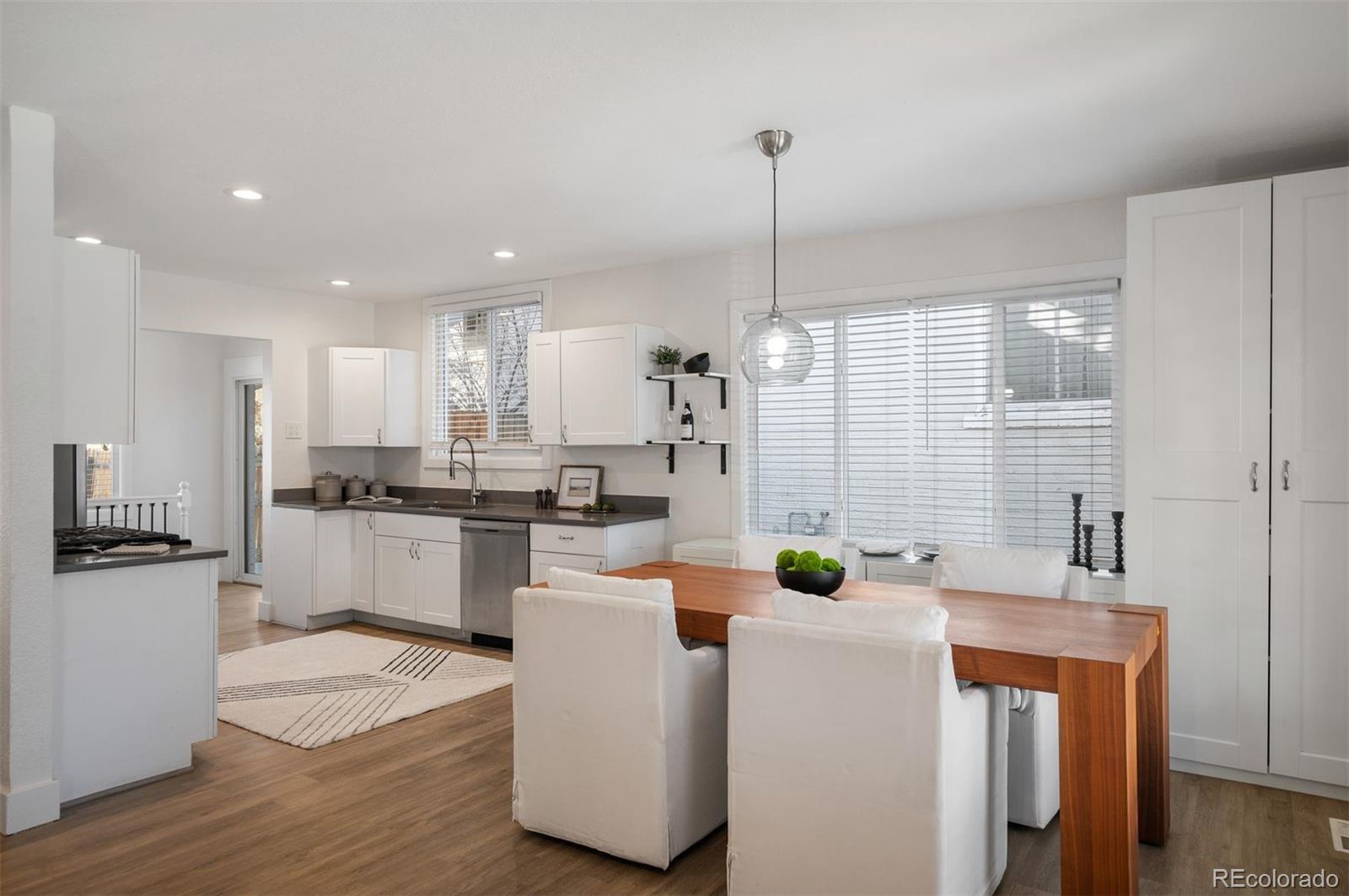 1422 Quebec Street Denver, CO 80220 - Photo 3 of 19 a kitchen with stainless steel appliances kitchen island a stove a sink a refrigerator and white cabinets with wooden floor