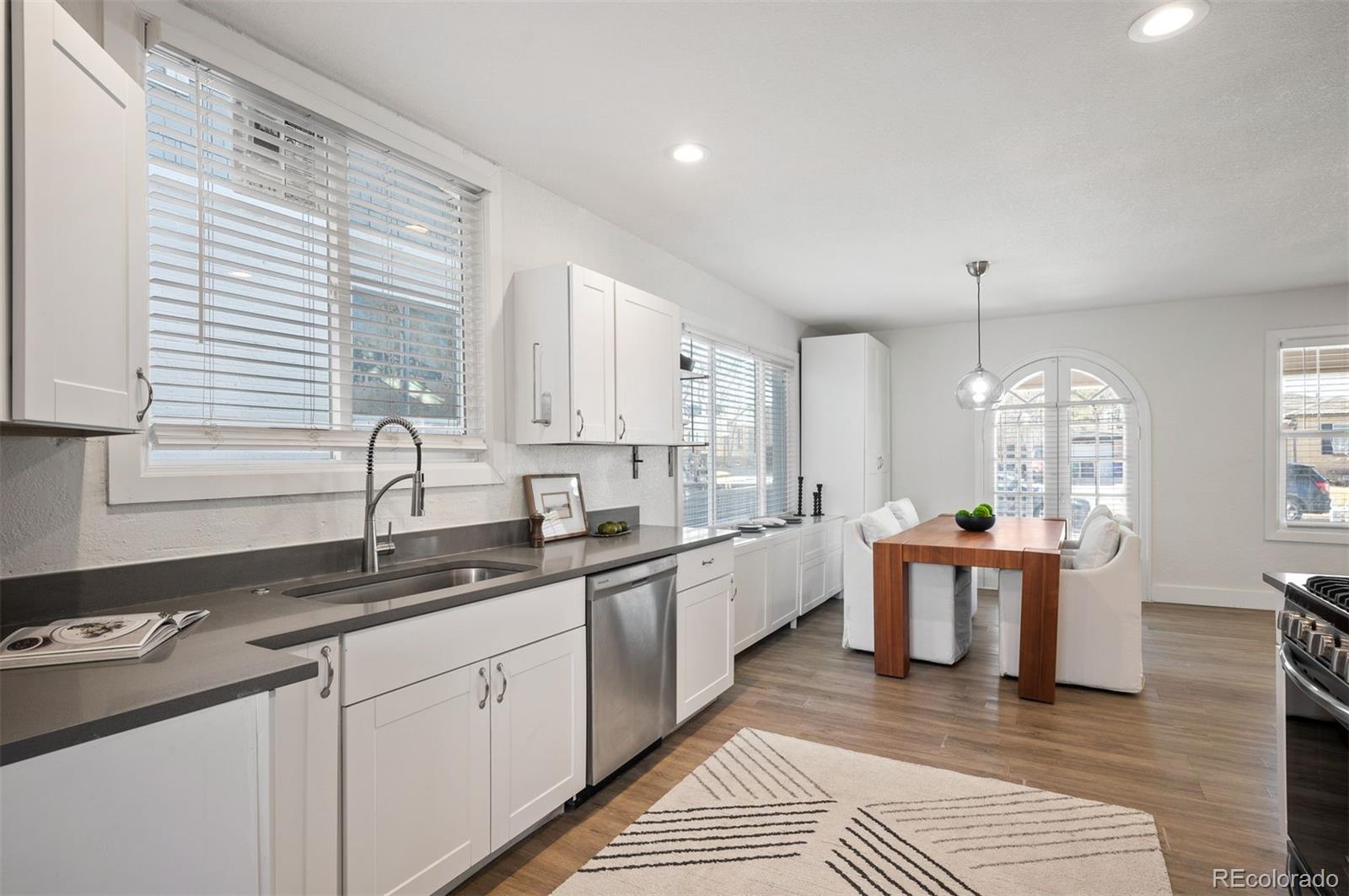 1422 Quebec Street Denver, CO 80220 - Photo 5 of 19 a kitchen with a sink stove cabinets and dining table