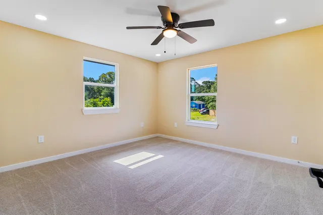 an empty room with windows and a ceiling fan