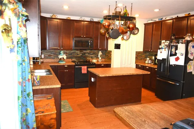 a kitchen with stainless steel appliances kitchen island granite countertop a table and chairs in it