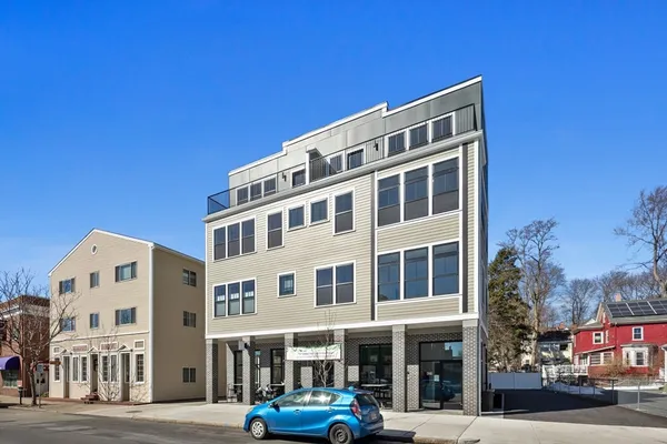 a front view of a building with lot of cars and trees