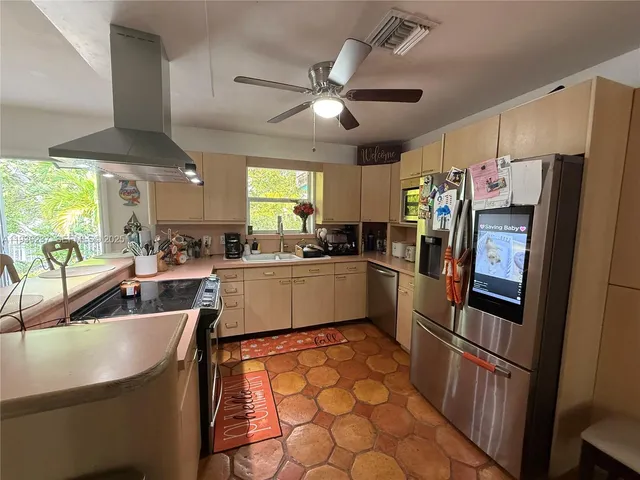 a kitchen with stainless steel appliances a refrigerator a sink a stove and white cabinets