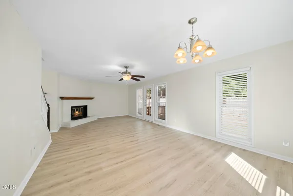 a view of an empty room with a chandelier fan