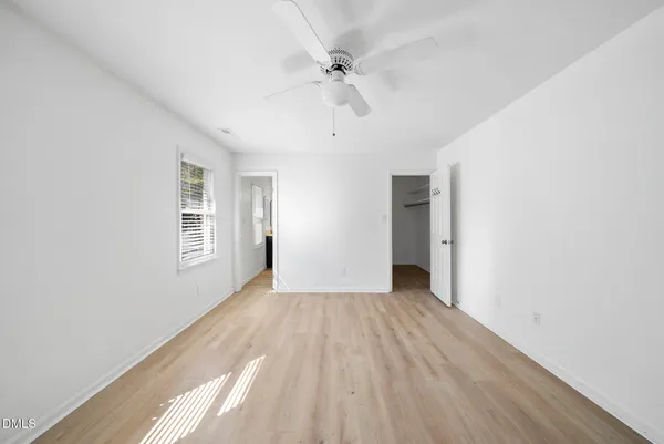 a view of an empty room with wooden floor and a window