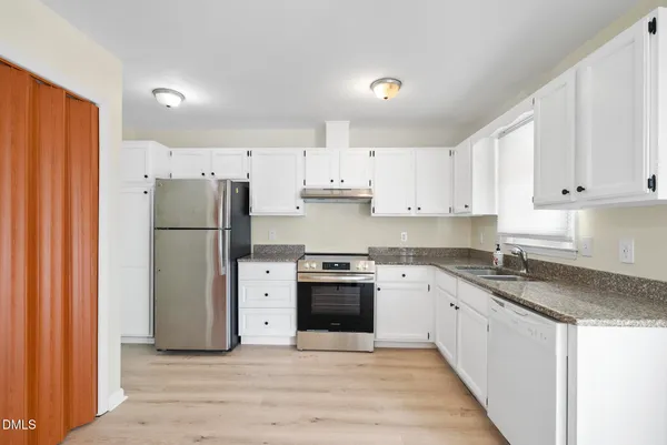 a kitchen with a refrigerator sink and white cabinets