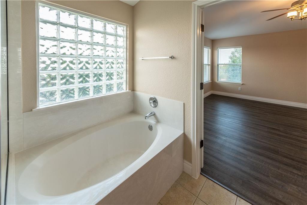 12017 Springs Head Loop Austin, TX 78717 - Photo 17 of 25 Indulge in a relaxing soak within this primary bathroom featuring a large built-in tub and decorative glass block window.