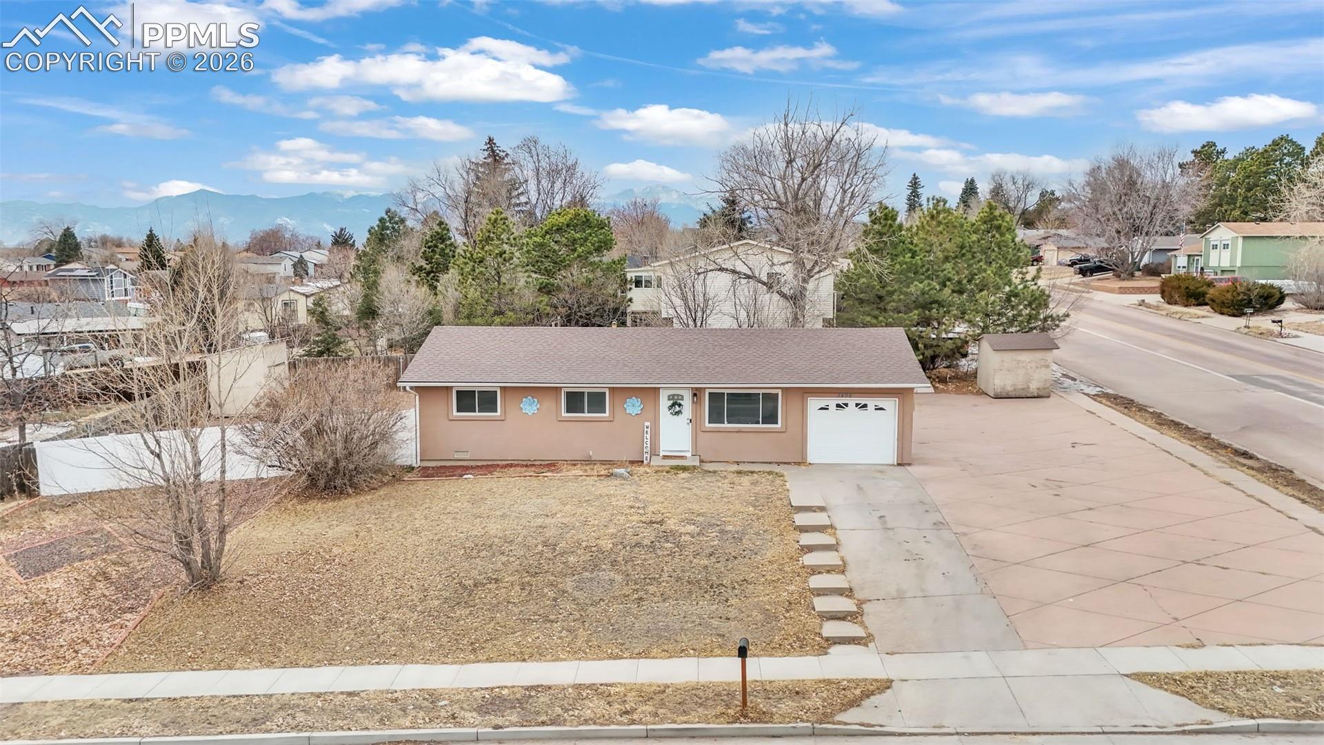1498 Peterson Road Colorado Springs, CO 80915 - Photo 38 of 44 Ranch-style home with concrete driveway, stucco siding, a garage, a residential view, and roof with shingles