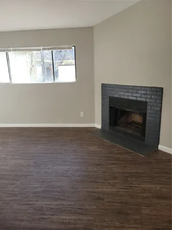 a view of empty room with wooden floor and a window