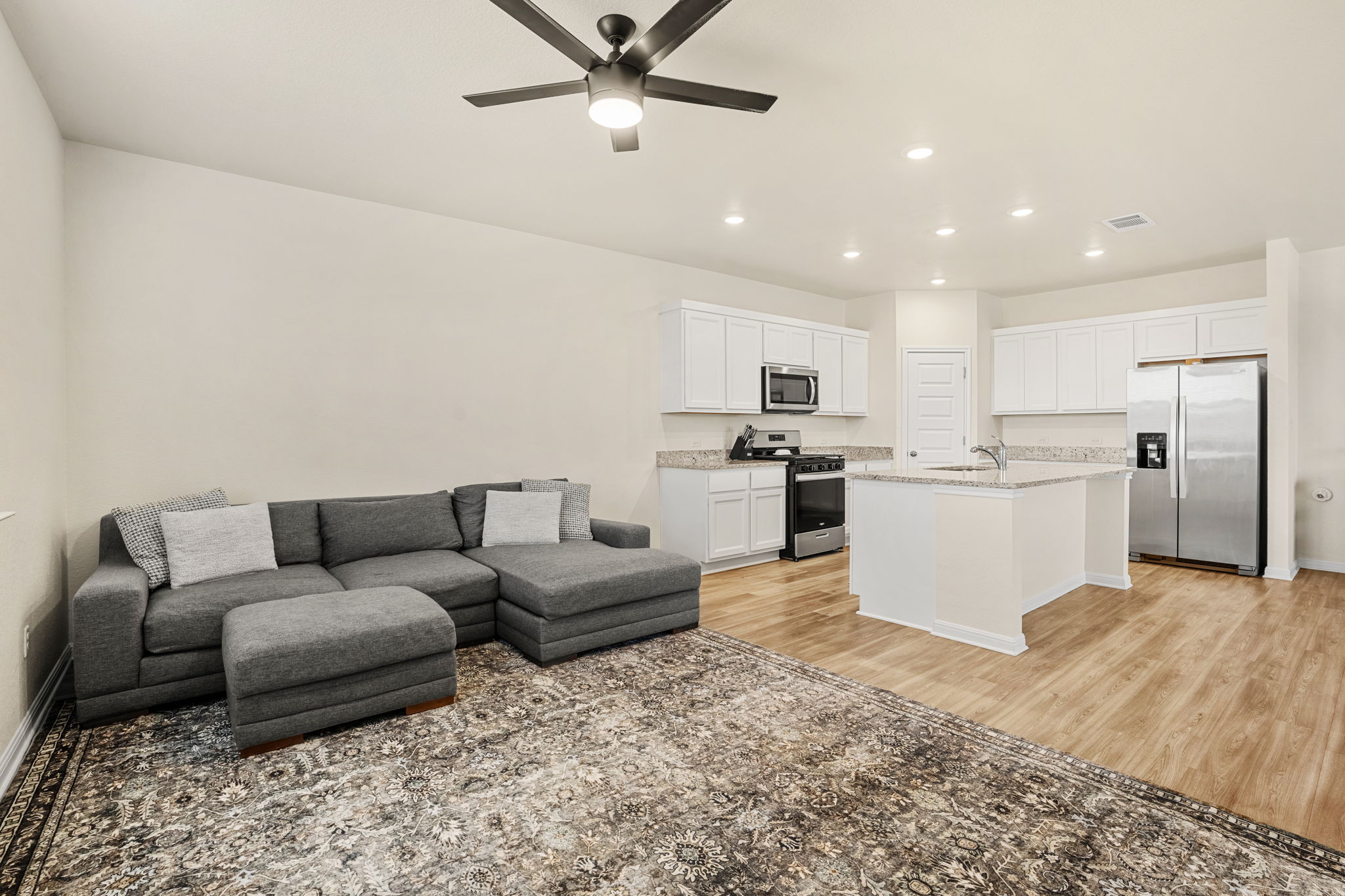 148 Hidalgo Lane Elgin, TX 78621 - Photo 14 of 38 An open concept living area boasts a modern kitchen with ample counter space and a living room with a ceiling fan.