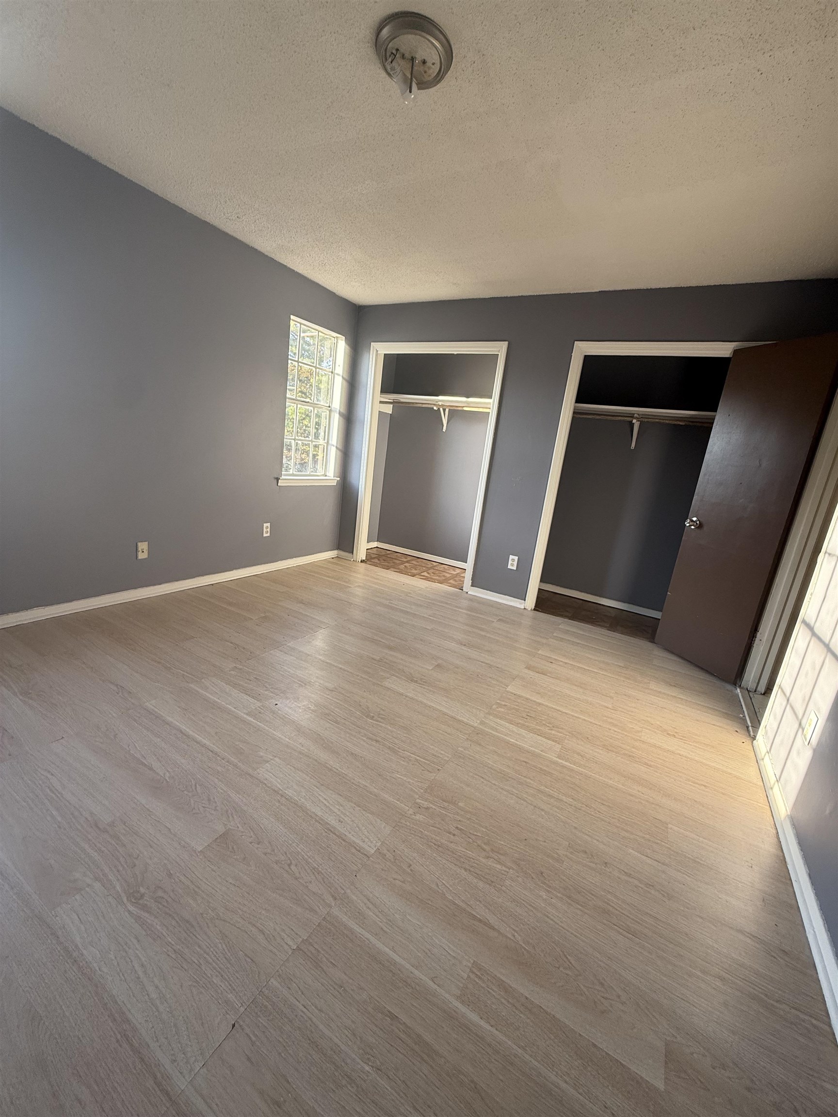 3091 Range Line Road Memphis, TN 38127 - Photo 9 of 13 Unfurnished bedroom featuring two closets, a textured ceiling, and light wood finished floors