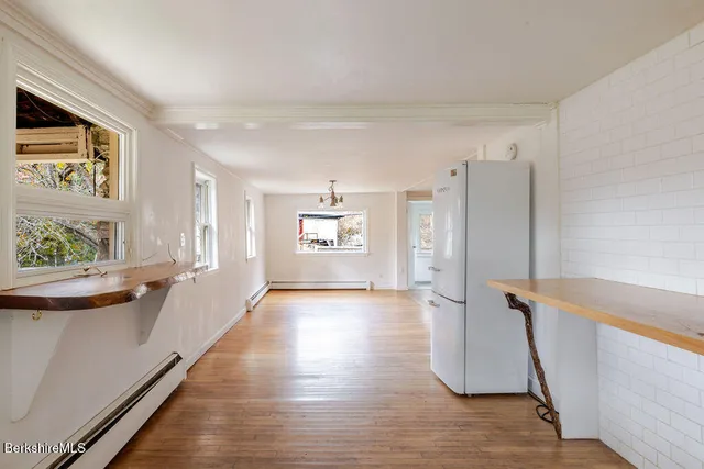 a view of an empty room with a window and wooden floor