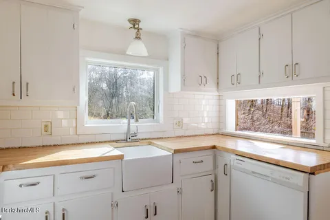 a kitchen with granite countertop a sink window and cabinets