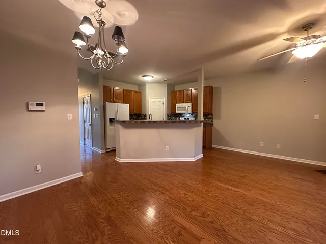 a view of a livingroom with a kitchen island stainless steel appliances a chandelier