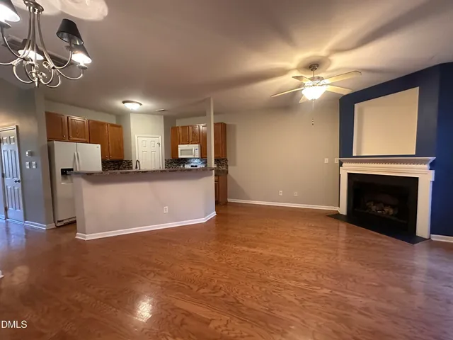 a view of a livingroom with a fireplace a ceiling fan and windows