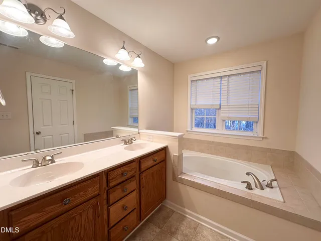 a bathroom with a tub double sink and a mirror