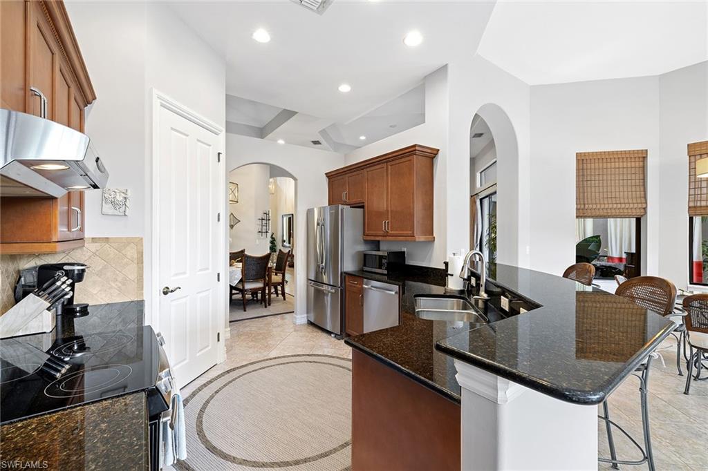 6513 Caldecott Drive Naples, FL 34113 - Photo 15 of 33 a kitchen with a sink a stove and chairs