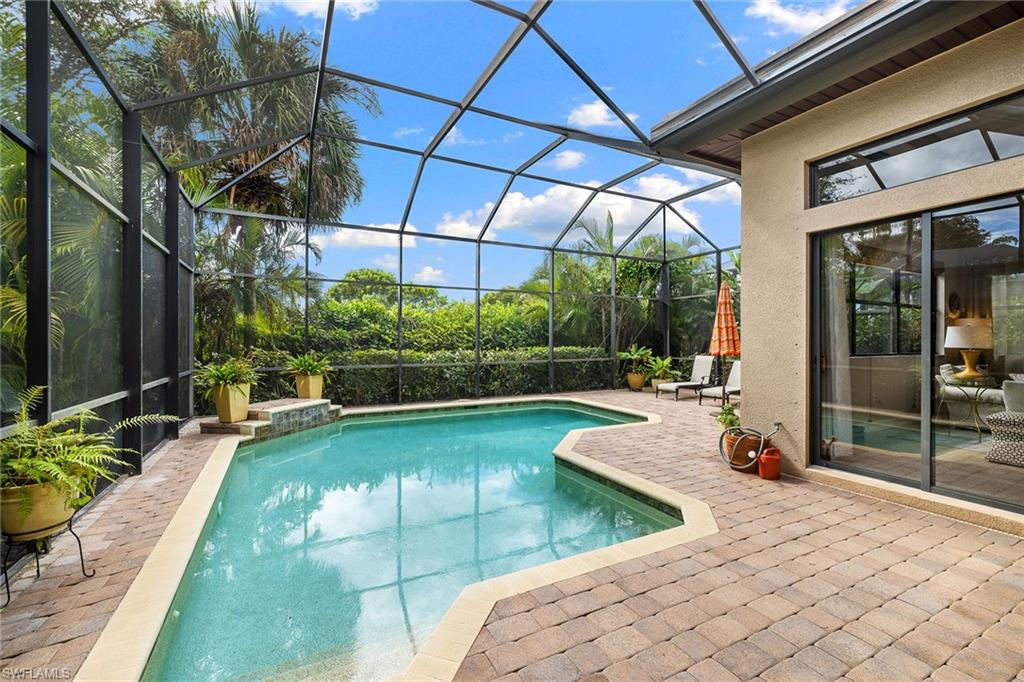 6513 Caldecott Drive Naples, FL 34113 - Photo 2 of 33 a view of a patio with table and chairs under an umbrella