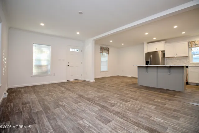 a view of a kitchen with kitchen island a sink wooden floor and a refrigerator