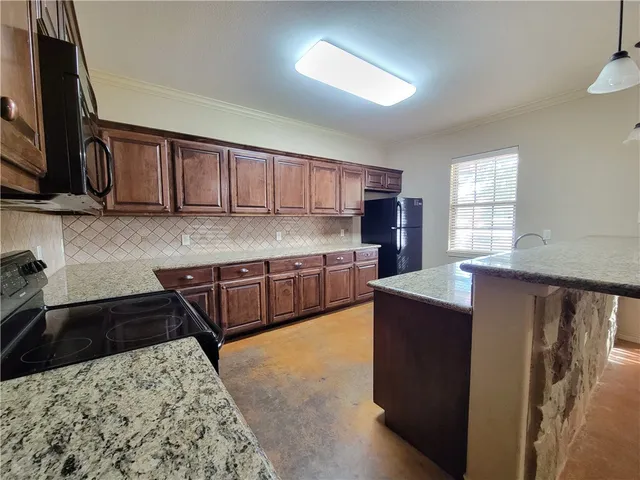a kitchen with stainless steel appliances granite countertop a stove a sink and a microwave