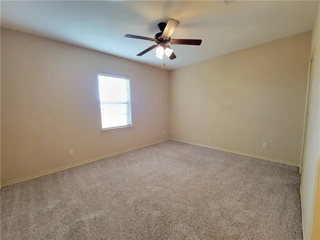an empty room with a chandelier fan and windows