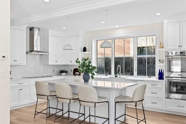a kitchen with stainless steel appliances kitchen island granite countertop a stove a sink and white cabinets with wooden floor