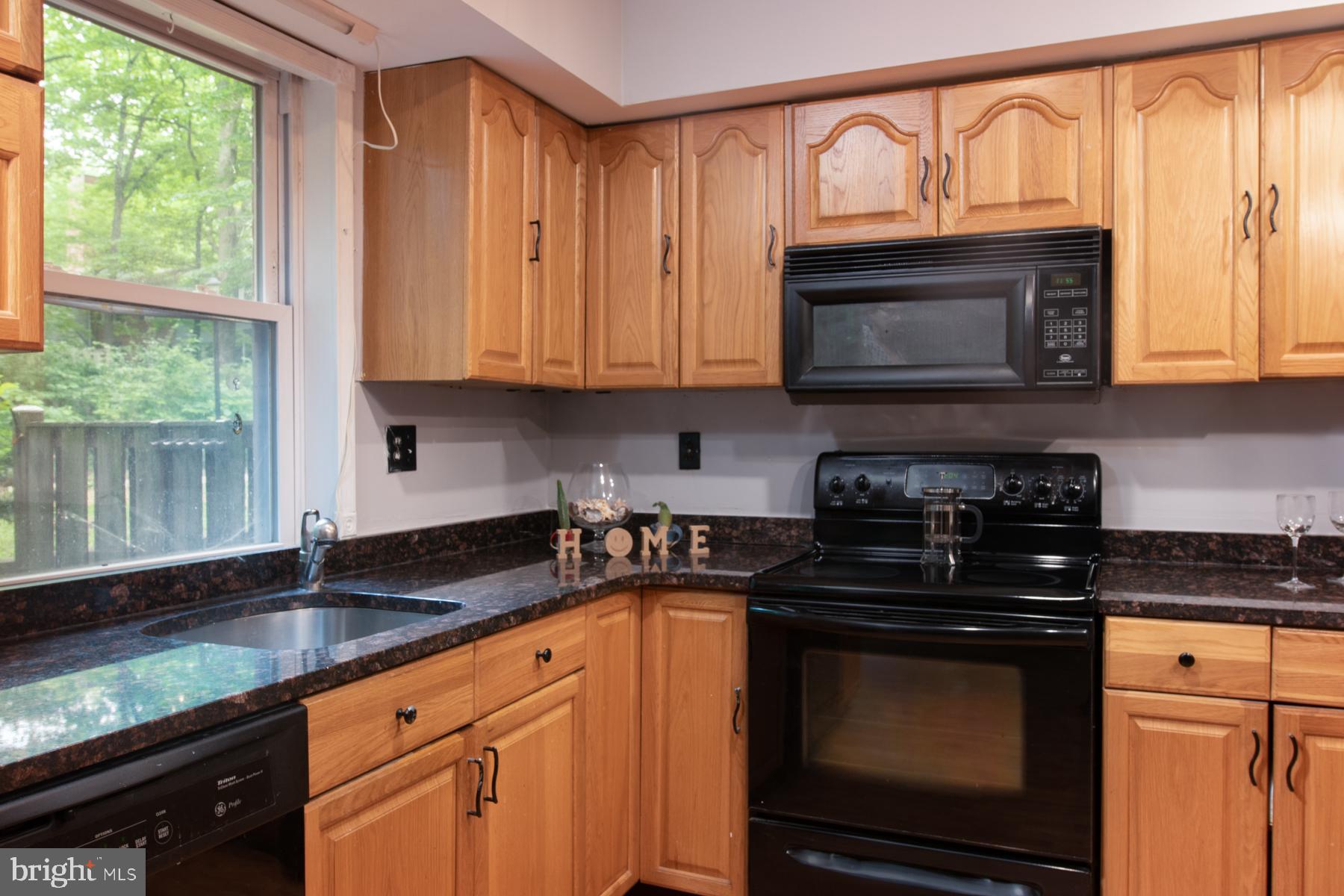 8603 Bradford Road, Unit 105 Silver Spring, MD 20901 - Photo 10 of 36 a kitchen with granite countertop a stove a sink and a microwave