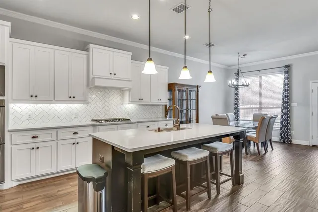 a kitchen with stainless steel appliances granite countertop a table chairs sink and cabinets