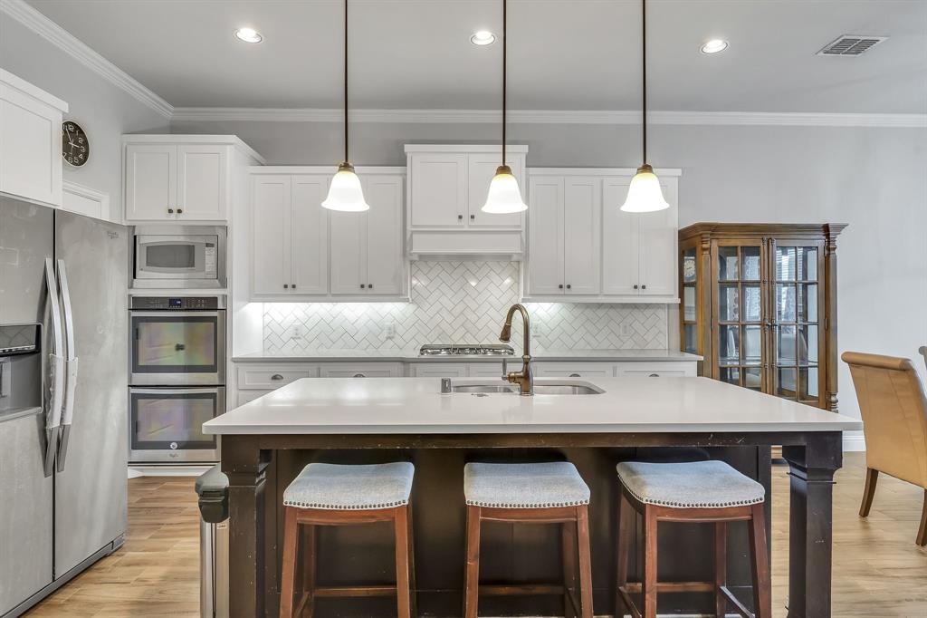 1306 Elizabeth Street Anna, TX 75409 - Photo 10 of 36 a kitchen with granite countertop a table chairs stainless steel appliances and cabinets