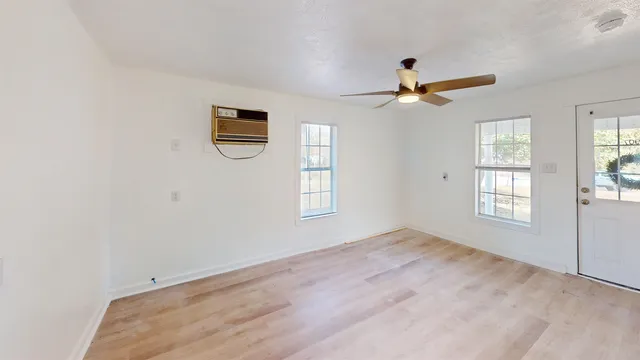 an empty room with windows and fan