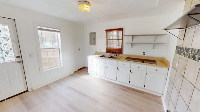 a view of a kitchen with wooden floor and white walls
