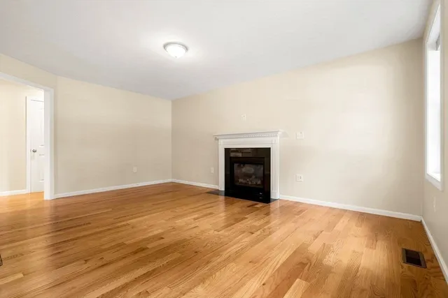 a view of empty room with wooden floor and fireplace