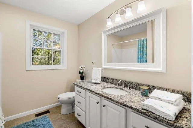 a bathroom with a granite countertop toilet a sink and a mirror
