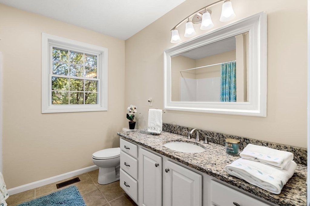 79 Bridle Road Billerica, MA 01821 - Photo 20 of 42 a bathroom with a granite countertop toilet a sink and a mirror