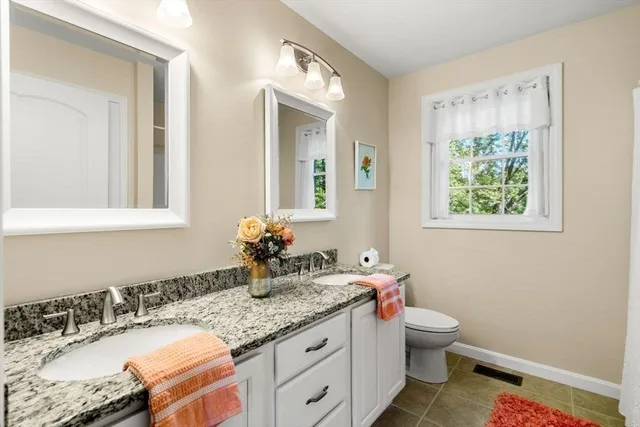 a bathroom with a granite countertop sink mirror vanity and toilet