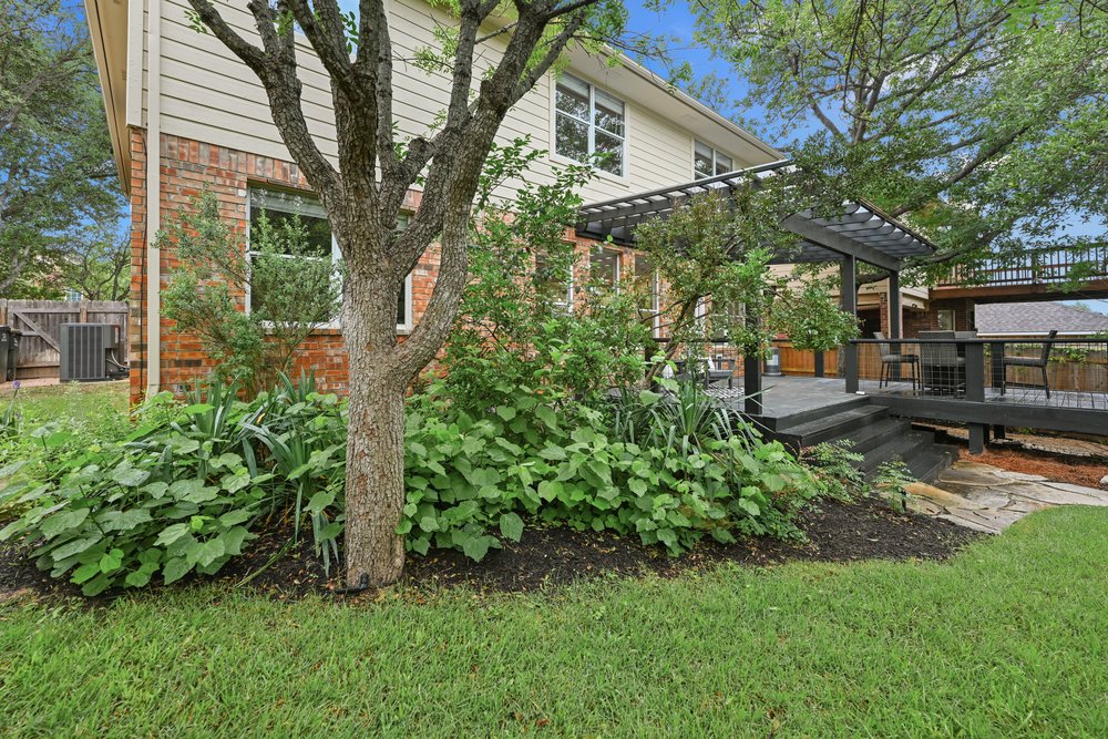 2823 Lantana Ridge Drive Austin, TX 78732 - Photo 31 of 34 a backyard of a house with plants and outdoor seating
