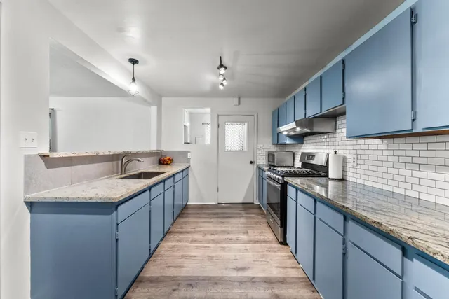 a large kitchen with granite countertop lots of counter space sink and stainless steel appliances