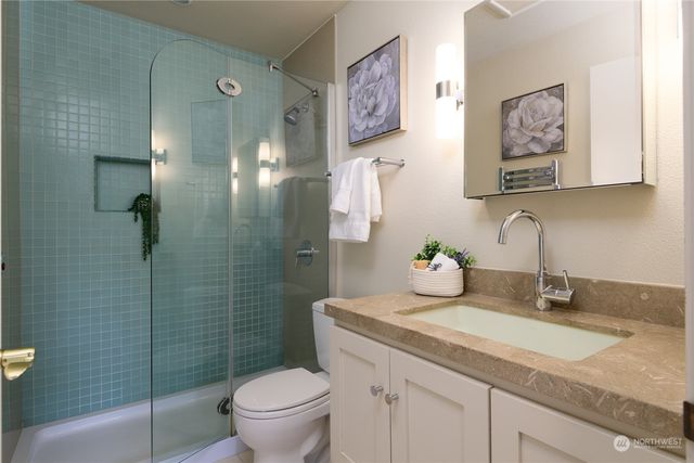 a bathroom with a granite countertop sink a toilet and shower