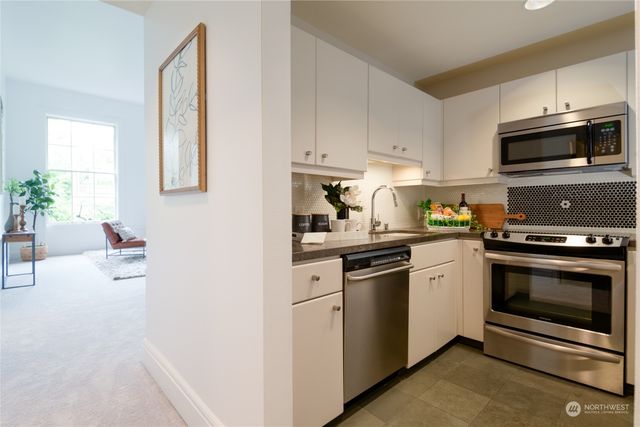 a kitchen with granite countertop white cabinets stainless steel appliances and wooden floor